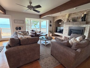 A living room with a fireplace, large windows, and a view of the ocean.