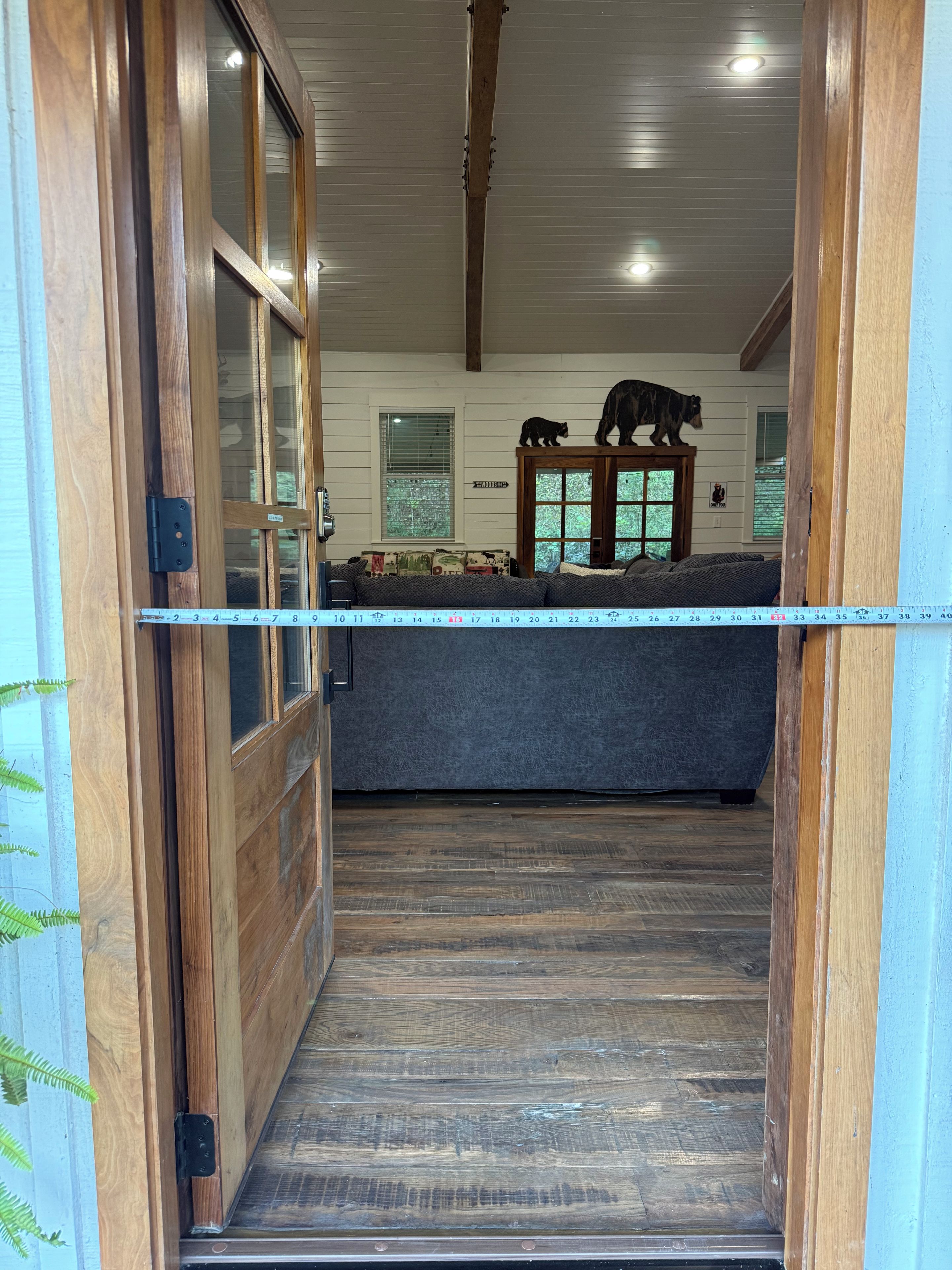 A wooden-framed doorway leading into a room with a sofa and two bear figurines on a cabinet.