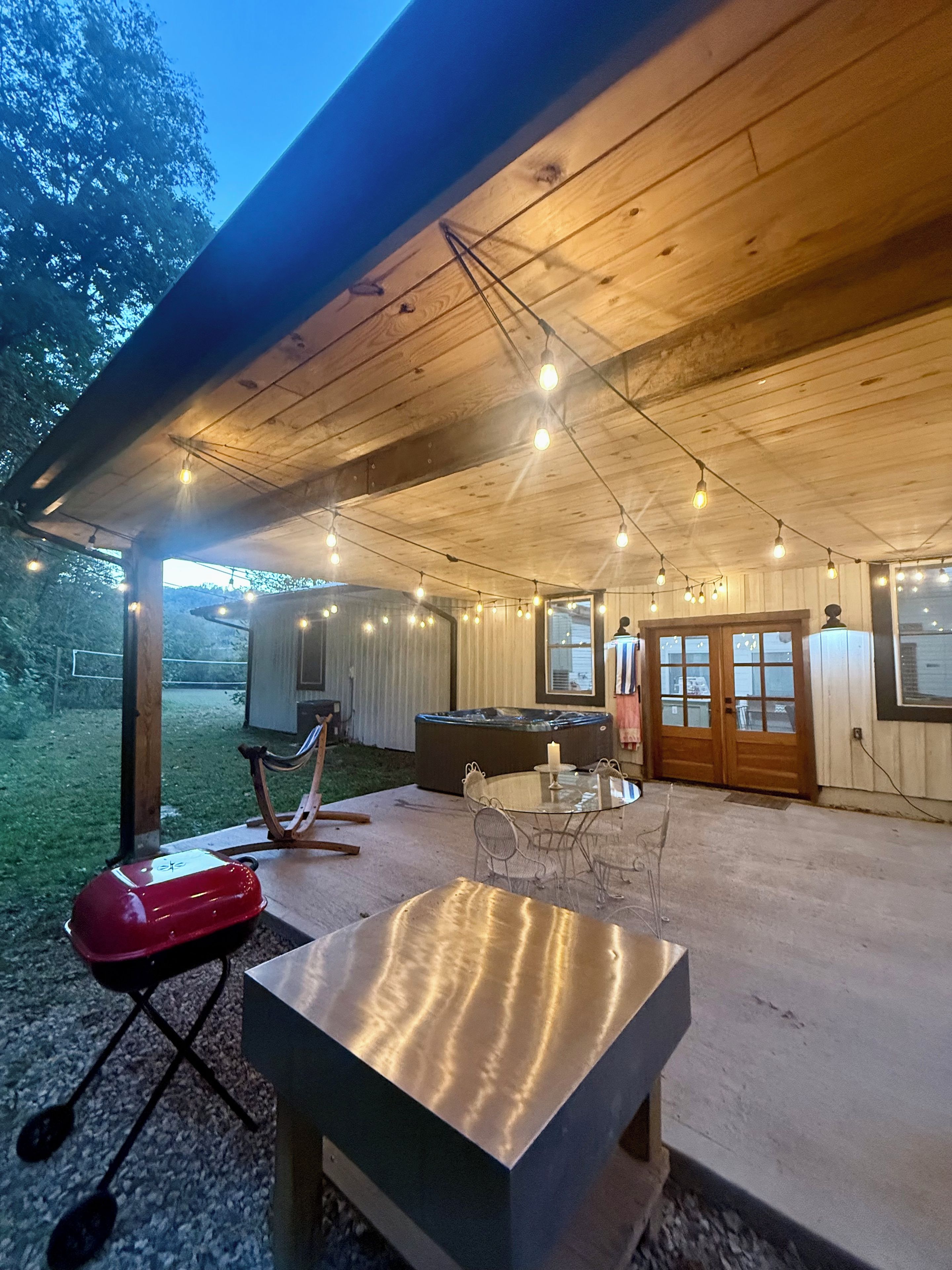 Eine überdachte Terrasse im Freien mit Tisch, Stühlen, einem Whirlpool und einer Holzbeschichtung.