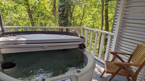 A hot tub on a wooden deck with a white railing, surrounded by lush greenery. - Loblolly Pines Adventure Camp Unit 3 (Eureka Springs)