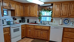 Cocina con armarios de madera, microondas, estufa y lavavajillas.