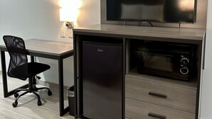 Een compact keukenhoekje met een magnetron, een kleine koelkast en een ingebouwde televisie.