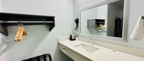 A bathroom with a white sink, a mirror, a towel rack, and a hairdryer.