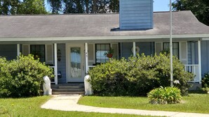 A two-story house with a porch, a front door, and a small front yard with bushes. - Enjoy Southern Hospitality in Kingland Georgia, Bring Pets, Plenty Parking (Kingsland)
