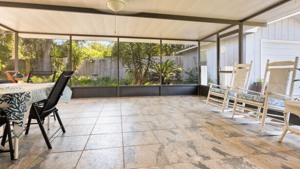 A covered patio with a table and chairs, large windows, and a view of the backyard. - Enjoy Southern Hospitality in Kingland Georgia, Bring Pets, Plenty Parking (Kingsland)