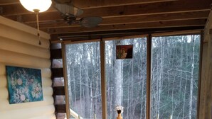 Un terrazzo in legno con un tavolo rotondo e sedie, un tappeto colorato e un quadro appeso al muro.