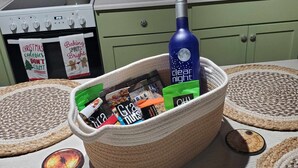Una cucina con un cesto intrecciato pieno di snack e una bottiglia d'acqua.
