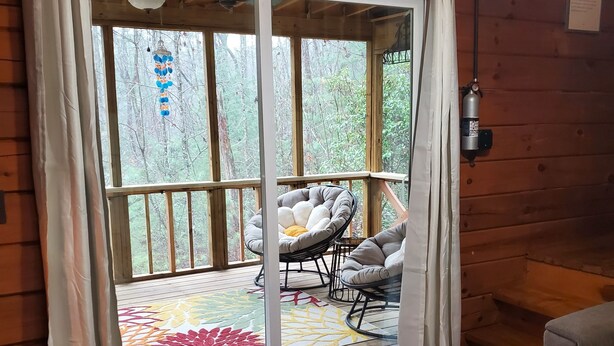 Interno di una baita in legno con una porta scorrevole in vetro che dà su un patio esterno.