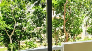 Un balcone con mobili in vimini e una porta vetrata che si apre su un giardino.