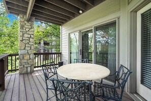 A covered patio with a stone pillar, a round table, and metal chairs. - Two Bedroom Villa in a Gorgeous, Gated Community near Silver Dollar City (Reeds Spring)