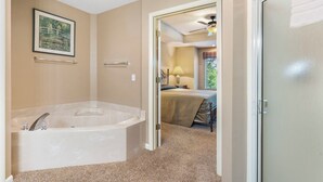 A bathroom with a bathtub, a shower, and a toilet. There is a framed picture on the wall and a door leading to another room. - Two Bedroom Villa in a Gorgeous, Gated Community near Silver Dollar City (Reeds Spring)