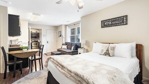 Ein kleines Schlafzimmer mit Bett, Schreibtisch und einer Küchenzeile.