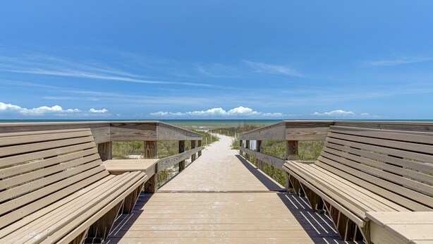 A wooden boardwalk leading to a beach with a clear sky. - Cozy Ground Floor Walkout w/Ocean View (Cocoa Beach)