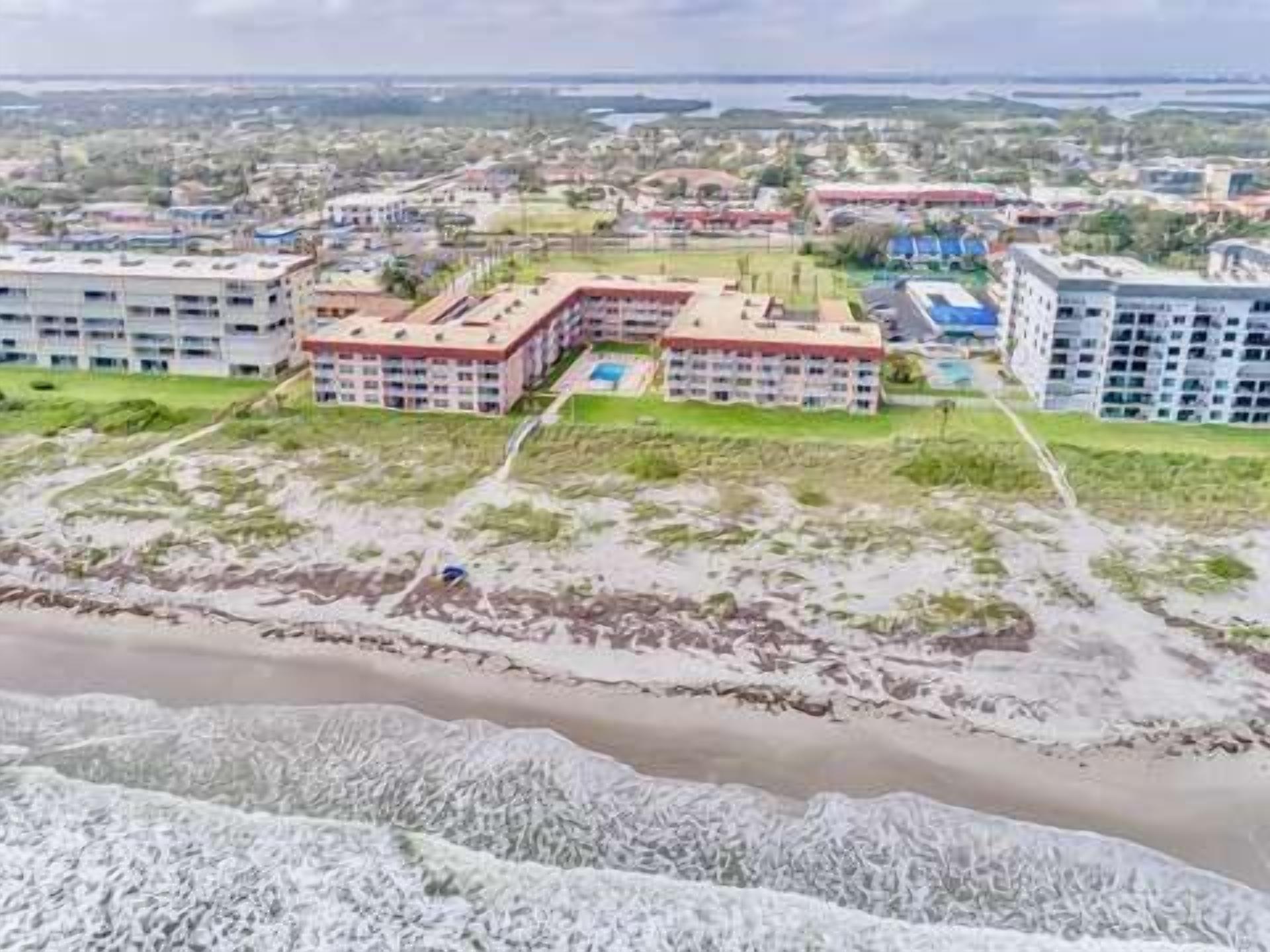 Un complejo hotelero frente al mar con varias edificaciones, una playa y un río.