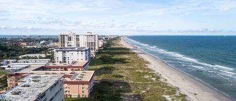 A coastal hotel with multiple buildings, a beach, and the ocean.