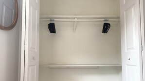 A white closet with two black hooks on the ceiling, a white door frame, and a grey carpet. - Cozy 2/1 Close to Theme Parks! (St. Cloud)
