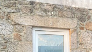 A stone wall with a white door featuring a frosted glass panel and a keypad lock. - Plátanos & River Views III (Ponte de Lima)