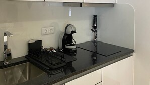A modern kitchen with white cabinets, a black countertop, and a coffee maker. - Plátanos & River Views III (Ponte de Lima)