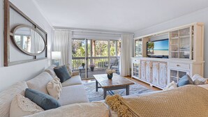 A living room with a sofa, coffee table, TV, and a view of the outdoors.