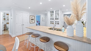 A kitchen with white cabinetry, a central island with stools, and a sink.