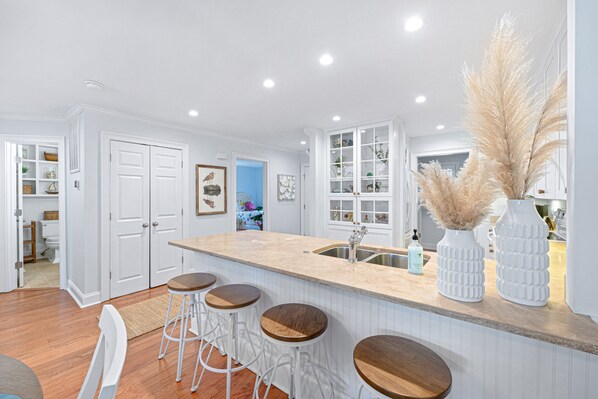 A kitchen with white cabinetry, a central island with stools, and a sink.