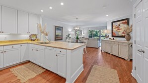 A spacious kitchen with white cabinetry, a central island, and a dining area with a view.