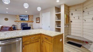 A modern kitchen with wooden cabinets, a granite countertop, and pendant lighting.