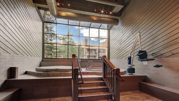 A wooden staircase leading to a spa area with a large window offering a view of buildings and trees.