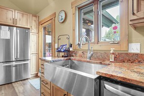 A kitchen with stainless steel appliances, wooden cabinets, a granite countertop, a sink, and a window with a view of greenery. - Private Hot Tub - Huge Covered Deck- Garage - On Ski Bus Route (Steamboat Springs)