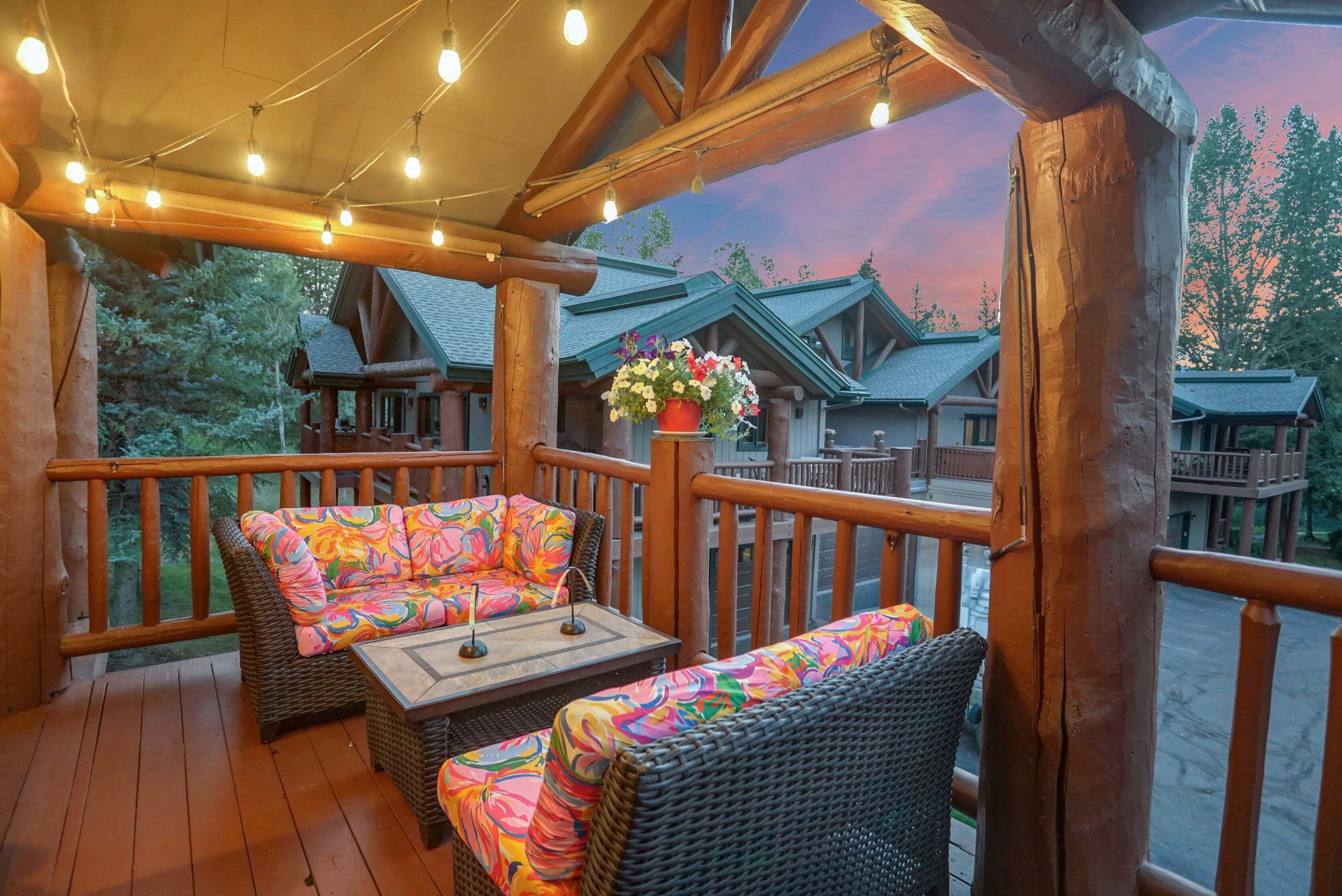 A wooden deck with wicker furniture and string lights.