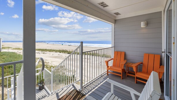 A balcony with a view of the beach, two orange chairs, and a small table. - BEACHFRONT!!! Updated 2 Bedroom 2 Bath  Condo (Ocean Isle Beach)