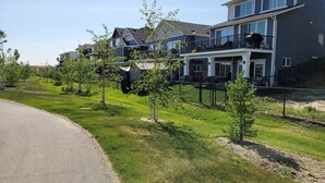 A residential area with modern two-story houses, a well-maintained lawn, and a clear sky. - Luxurious home away from home with AC in a quiet & Clean Neighborhood just 4 U (Airdrie)