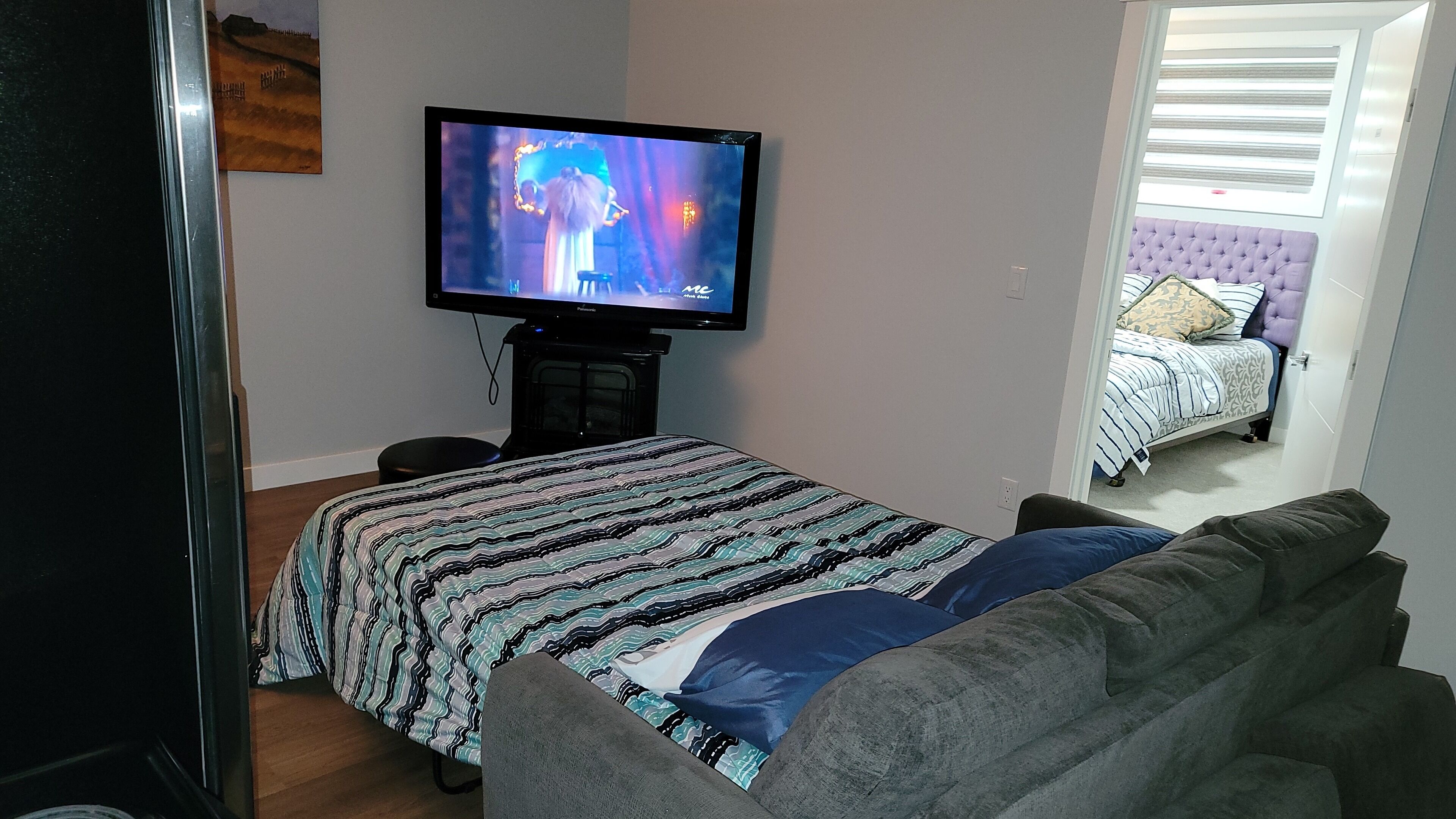 A bedroom with a bed, a television, and a window.