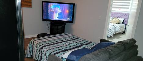 A bedroom with a bed, a television, and a window.