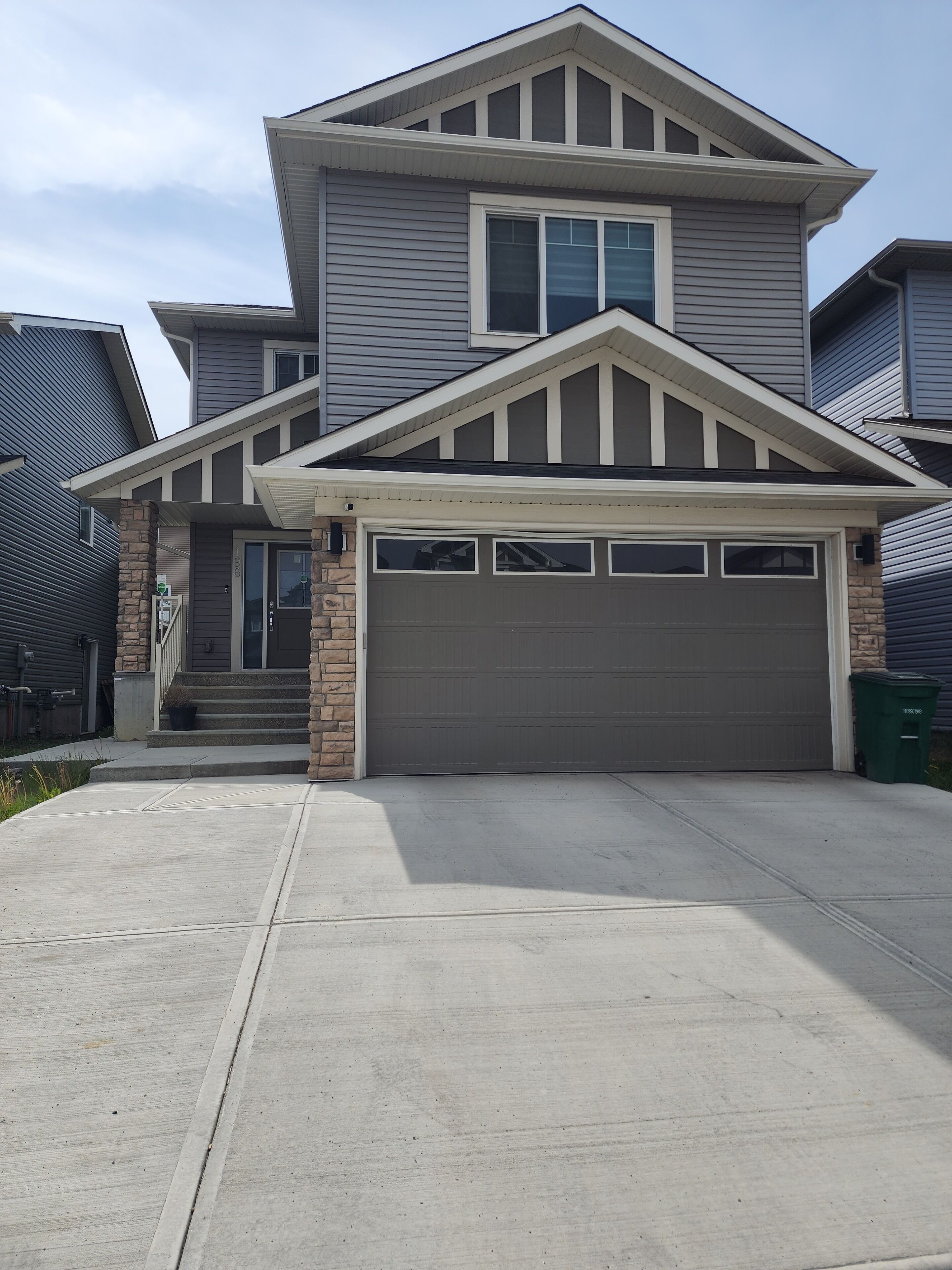 A two-story house with a garage, a front porch, and a stone pillar.