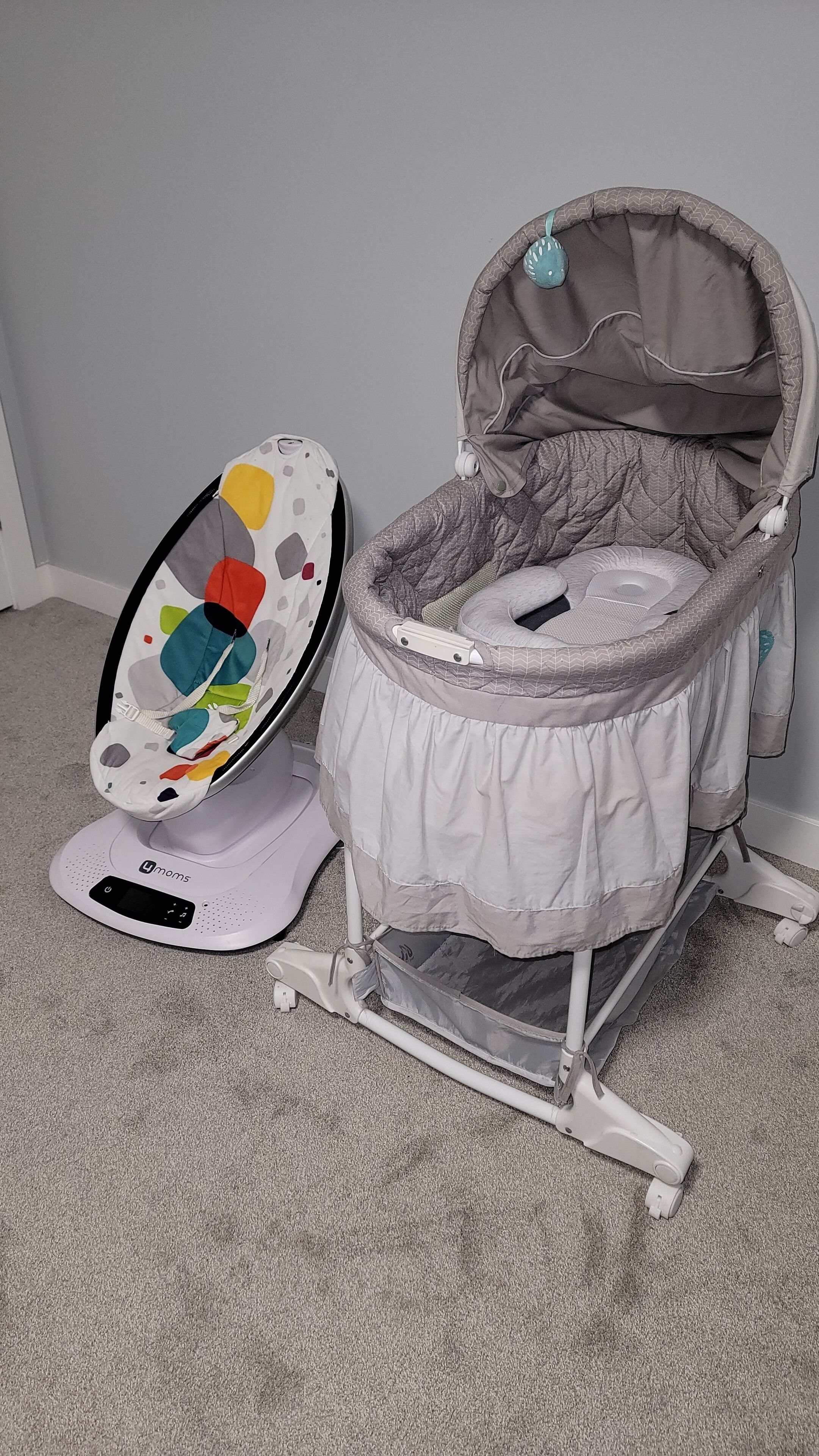 A portable baby rocker with a colorful seat and a white base.