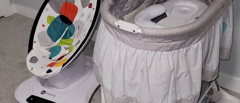 A portable baby rocker with a colorful seat and a white base.