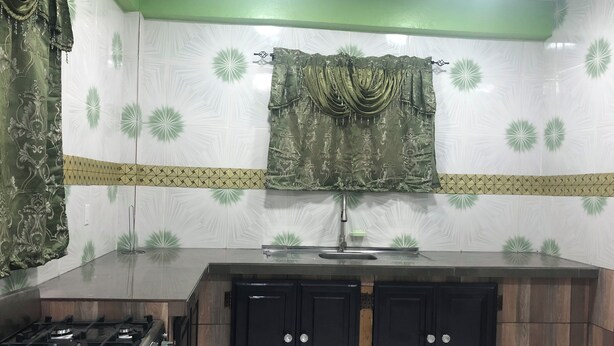 A kitchen with a gas stove, a sink, and wooden cabinets. - Superb apartment with AC located on the public road seawall (Georgetown)
