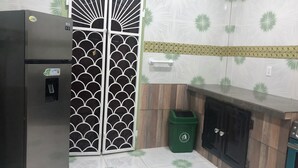A kitchen with a stainless steel refrigerator, a green trash bin, and a wooden cabinet. - Superb apartment with AC located on the public road seawall (Georgetown)