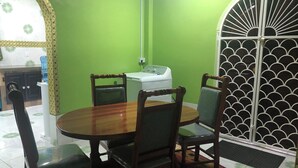 A dining area with a round wooden table and four chairs, a washing machine, and a decorative metal gate. - Superb apartment with AC located on the public road seawall (Georgetown)