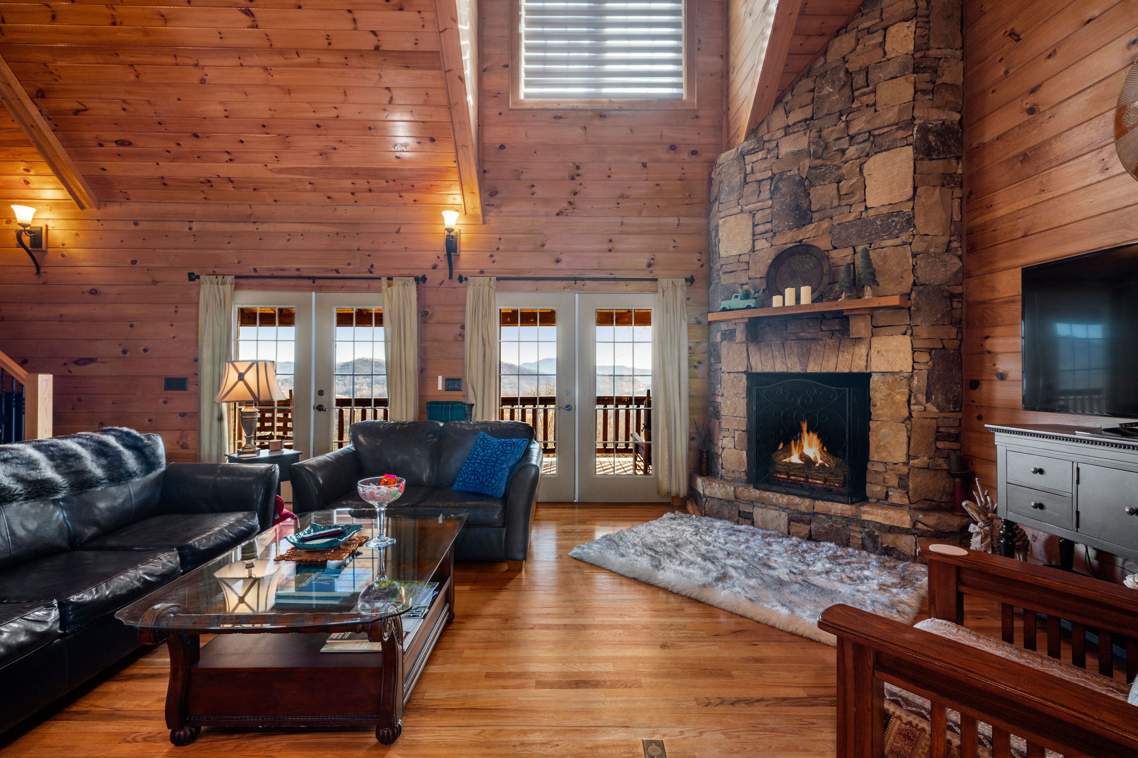 A cozy living room with a stone fireplace, leather sofas, and a glass coffee table.