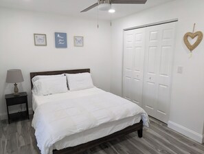 A bedroom with a bed, a nightstand, a ceiling fan, and a wardrobe. - Spacious Lake House retreat located in Clearwater FL, near beaches & shopping. (Clearwater)