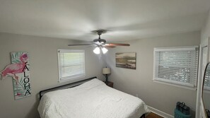 Cozy retreat with a single bed, ceiling fan, and wall art featuring a flamingo.