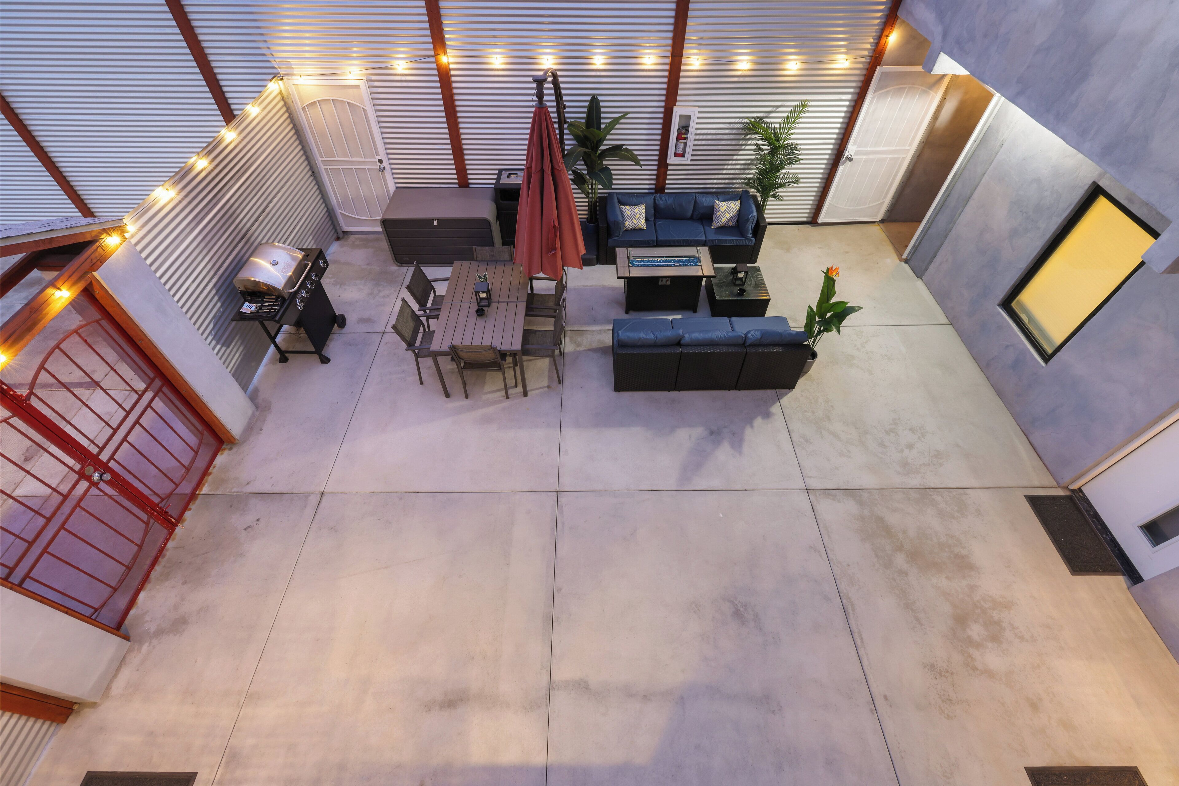 An outdoor patio area with a barbecue grill, seating arrangements, and a potted plant.