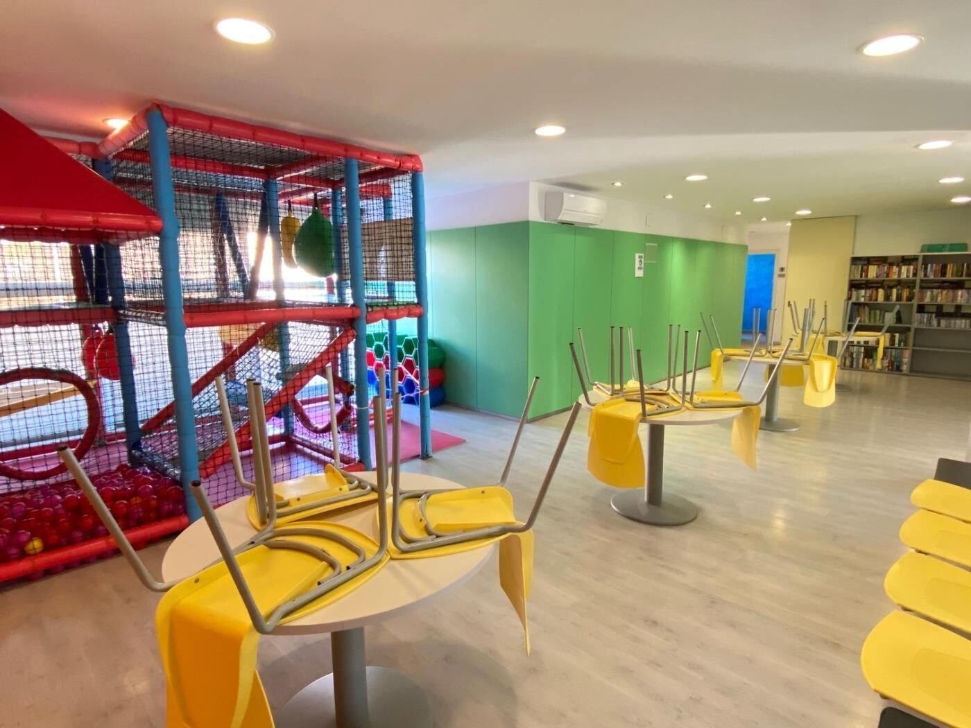 A children's play area with a climbing structure and yellow chairs arranged for seating.