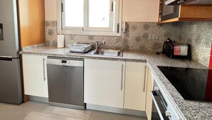 Eine Küche mit einem Edelstahl-Kühlschrank, einem Geschirrspüler, einer Spüle mit Fenster darüber und einem Toaster auf der Arbeitsfläche.
