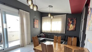 Ein moderner Essbereich mit Holztisch und -stühlen, einer schwarzen Ledersofa und einem großen Fenster mit Vorhängen.