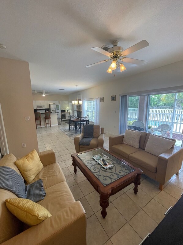 A spacious living room with a large sofa, a coffee table, and a ceiling fan.