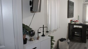 A room with a white dresser, a small plant, a globe, and a scale on the wall.
