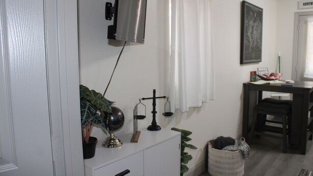 Ein Zimmer mit weißem Schminktisch, einer kleinen Pflanze, einem Globus und einer Waage an der Wand.